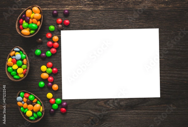 Obraz Chocolate easter eggs and colored sweets on a wooden background.  Place for text or logo.