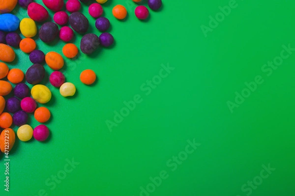 Obraz Colored candies on green background.