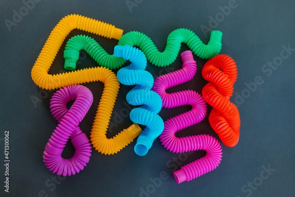 Fototapeta Colorful anti-stress fidget pop tube sensory toy on grey background. Flat lay.