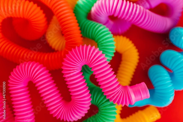 Fototapeta Colorful anti-stress fidget pop tube sensory toy on red background. Flat lay.