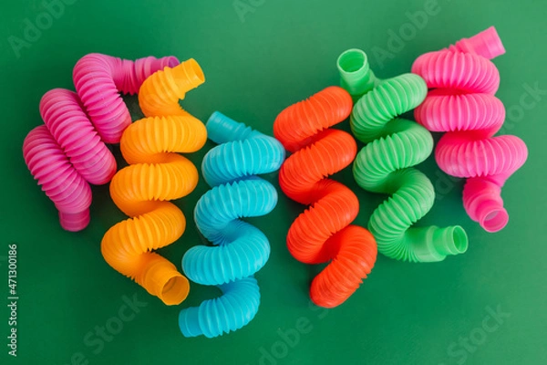 Fototapeta Colorful anti-stress fidget pop tube sensory toy on green background. Flat lay.
