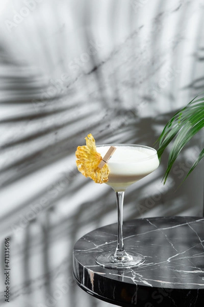 Fototapeta pina colada cocktail with shadow on jight backround. Pina Colada cocktail with decorations on marble table light background