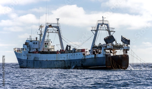 Fototapeta Large fishing trawler is fishing for fish and seafood in the ocean.