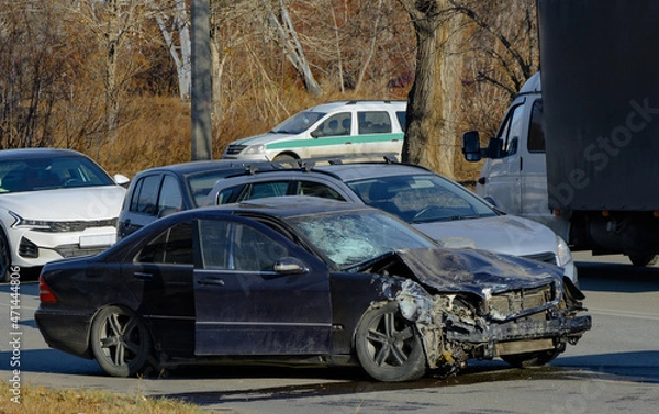 Fototapeta a black passenger sedan stopped after a serious accident with a broken hood and a broken windshield. fuzzy focus