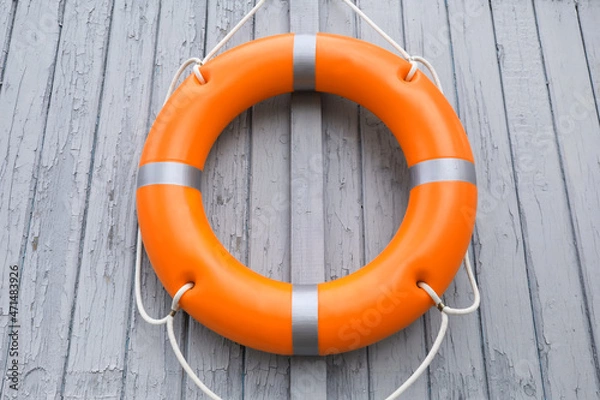 Fototapeta Orange life buoy hanging on light wooden wall