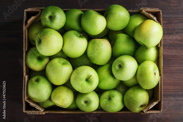 Obraz Ripe and juicy Green apples in a box on a wooden table.