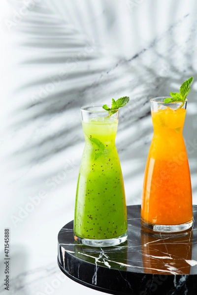 Fototapeta lemonade jug on marble table with copy space on light background. Peach and green lemonade with ice and mint