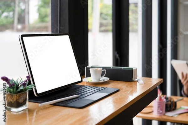 Fototapeta Computer tablet with white screen, coffee cup and book on wooden table.