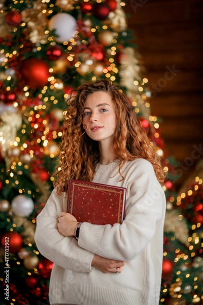 Fototapeta A beautiful girl portrait in a Christmas interior. Christmas tree, decorated fireplace, lots of gifts, Christmas theme. Cozy atmosphere.