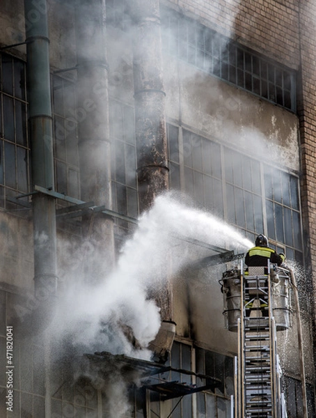Obraz Firefighter on a lift extinguishes an abandoned building