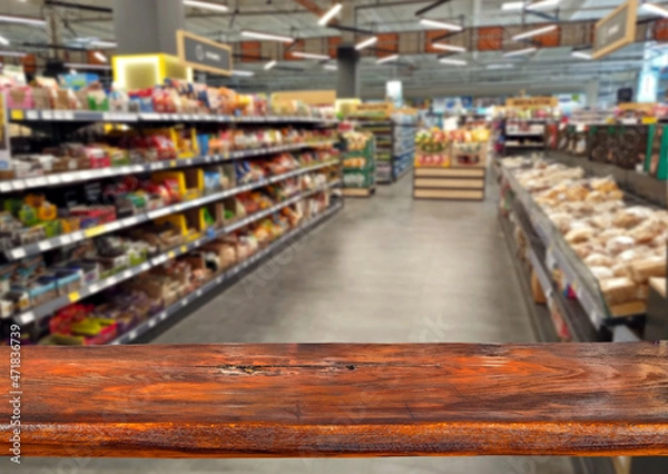 Fototapeta Wooden board on a background of blurred rows with products. Grocery store. Sharpness on the board. Place for product advertising. Free space for design and goods. Layout for products.
