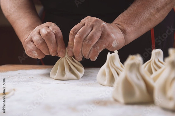 Fototapeta Chef cook making khinkali  on wooden table. Process preparation georgian meal. food concept.