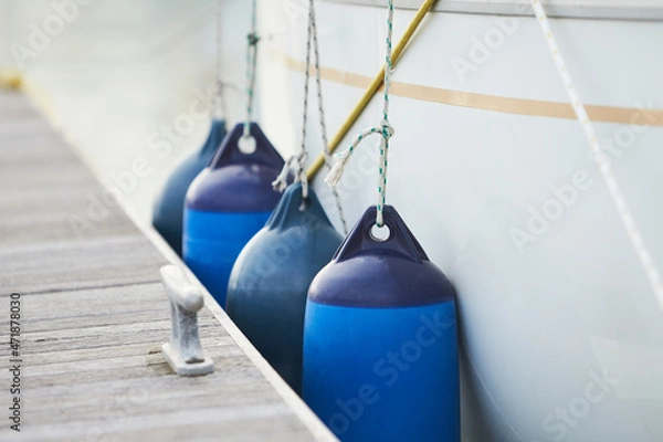 Obraz White fenders suspended between a boat and dockside for protection. Maritime fenders