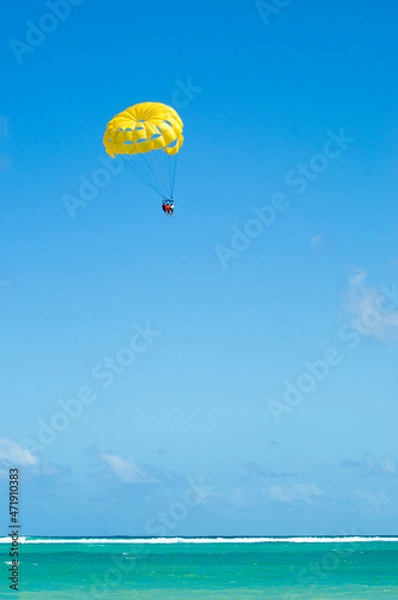 Fototapeta Yellow parasailing  with 3 people towed at beach in Punta Cana
