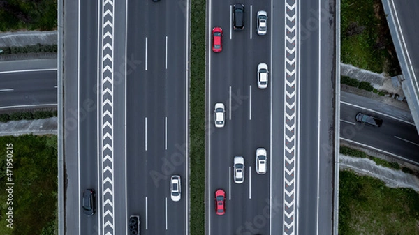 Fototapeta Top down aerial view from drone on modern traffic junction of multiple lane highway road in metropolis city. Heavy traffic on motorways. Elevated curved roads, clover shape bridge with no speed limit.