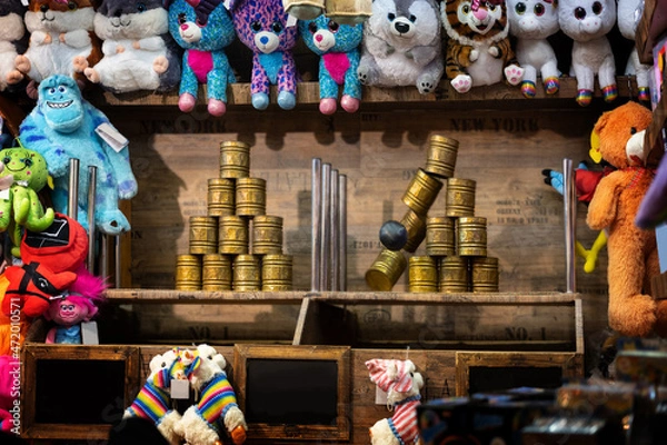 Fototapeta Throwing booth at the Christmas market with cans, ball and colorful plush toys as prizes, selected focus, motion blur