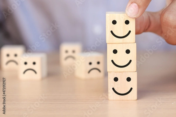 Obraz Hand holding wooden cube with smiley face icon and sad face icon. Customer Service Satisfaction Concept