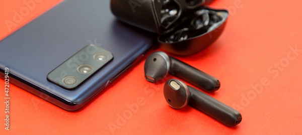 Fototapeta Audio headphones without wires included with a new smartphone on offer
