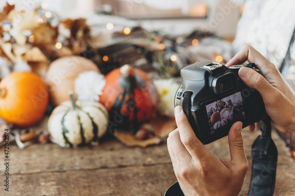 Obraz Photographer holding camera and taking photo of halloween pumpkins against a rustic autumn background