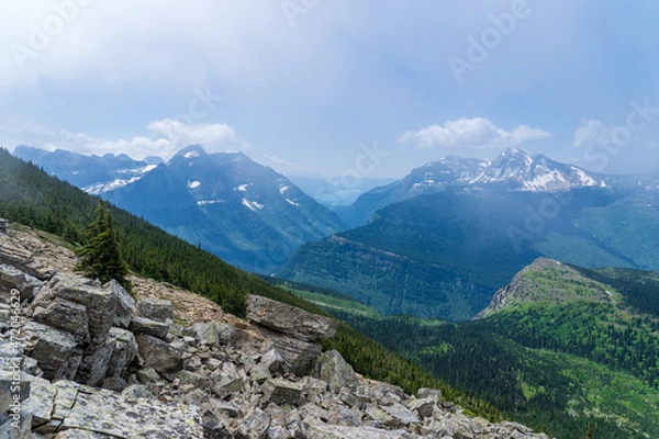 Fototapeta View of Lake McDonald from a distance through the clouds and trees in Glacier National Park, as viewed from hiking on the Highline Trail by the Going to the Sun Road on a sunny summer day