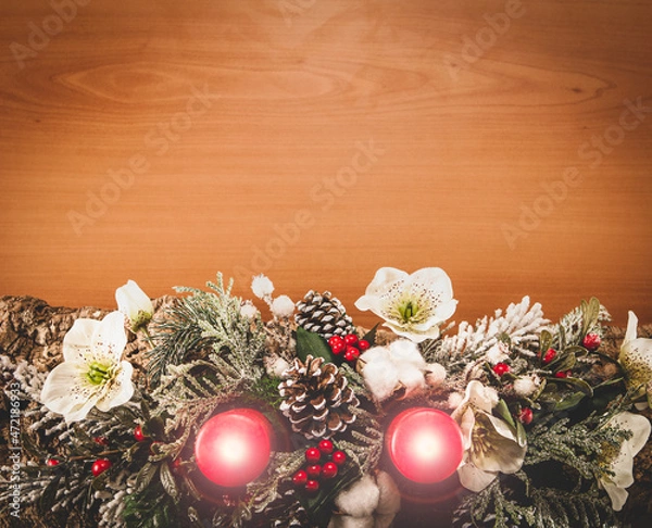 Fototapeta Christmas composition made with cork bark, pine, white flowers, red berries, red candles with hot flame, pine cones and snowy branches on wooden table flat lay view