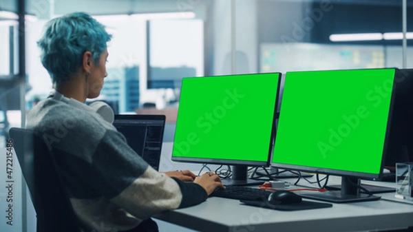 Fototapeta In Diverse Office: Female Programmer is Working on Green Screen Computer, Chroma key and Coding Language User Interface. Digital Entrepreneur Creating Software, e-Commerce App Design. Over Shoulder