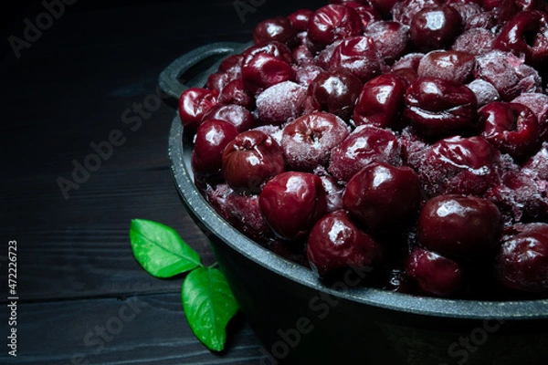 Obraz A lot of frozen cherry without sticks on a wooden black background.Vitamins and a healthy diet