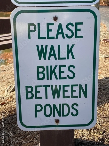 Fototapeta Please Walk Bikes Between Ponds Sign