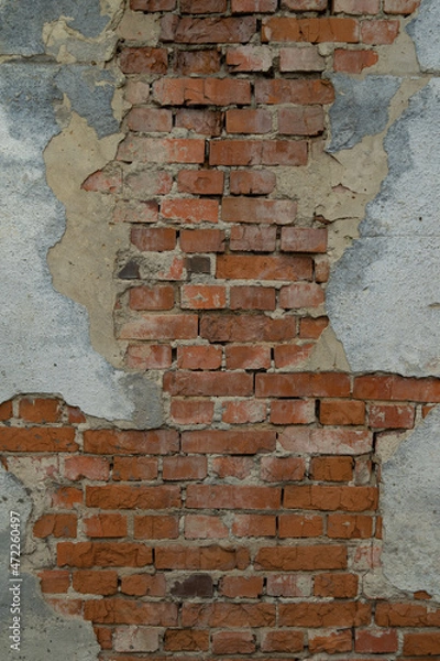 Fototapeta Texture of an old brick wall. Brick wall background with peeling plaster. Brick wall with fallen plaster.