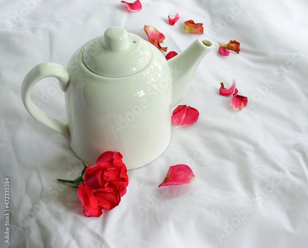Obraz White teapot and rose petals on a white background
