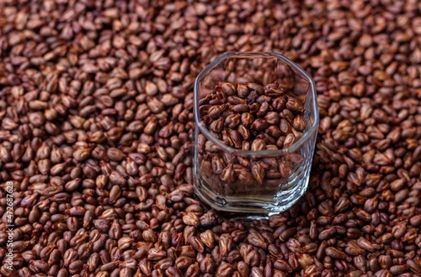 Fototapeta 
A small glass with dried grape seeds on the background of their scattering
