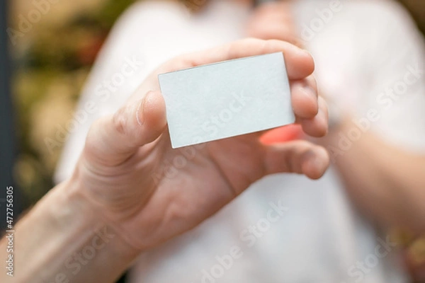 Fototapeta Hand holds a white piece of paper for notes