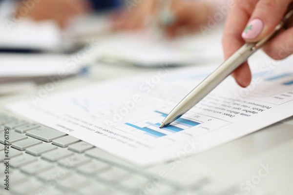 Obraz Man going through financial report paper with silver pen