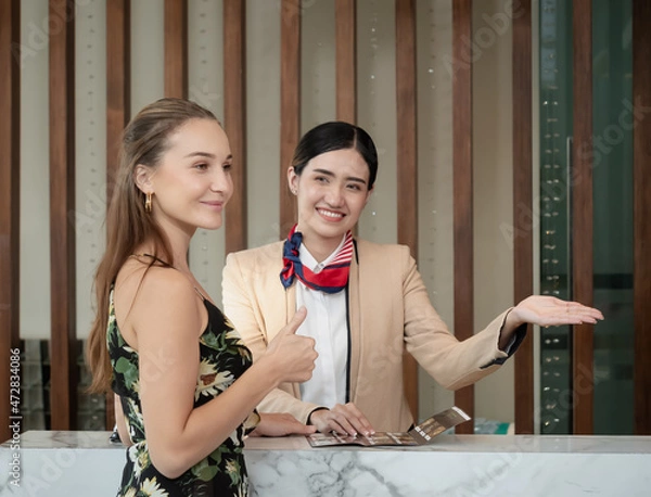 Fototapeta The charming young lady was pleased with the receptionist's advice on the hotel's services to the guests, Selective focus on the customer