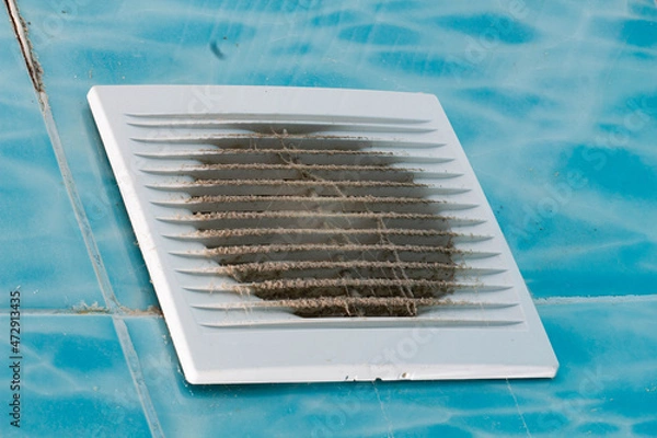 Fototapeta Very dirty bathroom fan. Heavily soiled fan with white plastic grill. Electric equipment needs cleaning. Blue tiles with a pattern in the bathroom. The spider twisted a web in the toilet