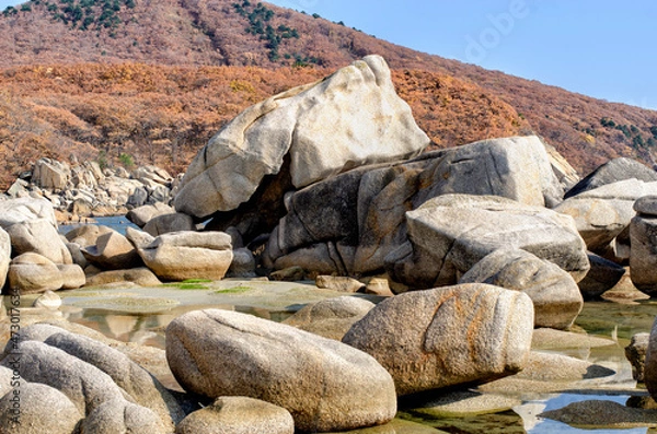 Obraz A group of granite boulders on the seashore at the foot of the mountain range.