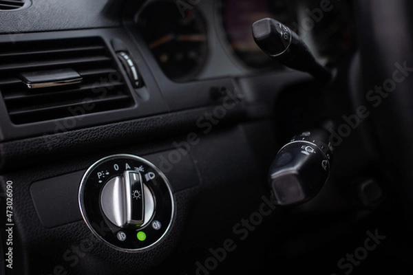 Fototapeta An unrecognizable male driver activates lights or turn signals on the control lever behind the steering wheel of the car.