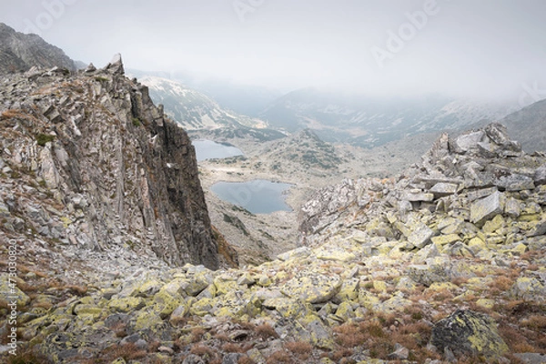 Obraz View of glacier lakes on Rila mountain through the rocky, pointy, mountain cliffs under a moody sky