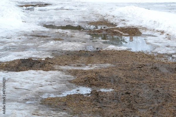 Fototapeta Winter Ground Covered With Thawing Snow. Slush and mud on road from melting snow on the road during spring thaw.
