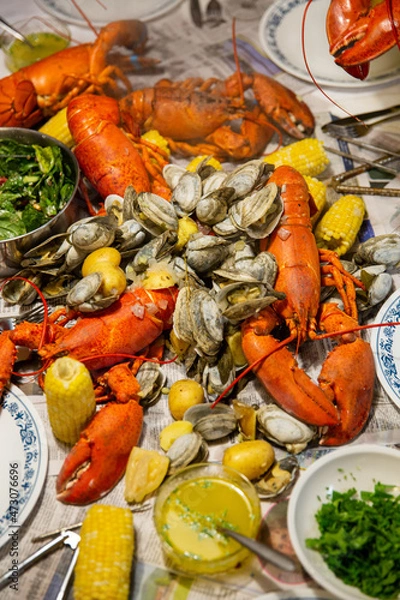 Fototapeta Bright Red Lobster Seafood Bake with Corn Cob and Bowl of Salad