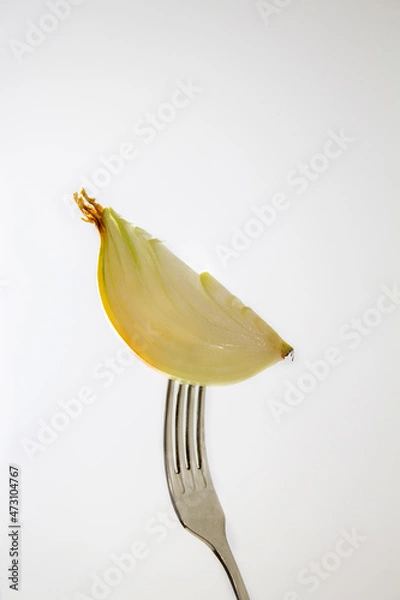 Fototapeta Onion on a fork, close-up. On white background. Creative
