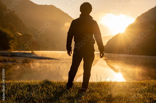 Obraz 湖畔で朝日を見る人の写真