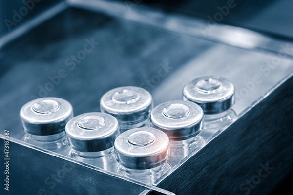 Fototapeta Glass bottles in production in the tray of an automatic liquid dispenser, a line for filling medicines against bacteria and viruses, antibiotics and vaccines.
