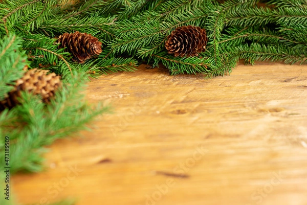 Obraz Branches of a Christmas tree and cons on a brown wooden background. Close-up, place for text, layout for design