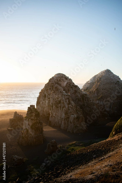 Fototapeta A beautiful beach with two big rocks on it, at sunset, in a beautiful landscape with nice views
