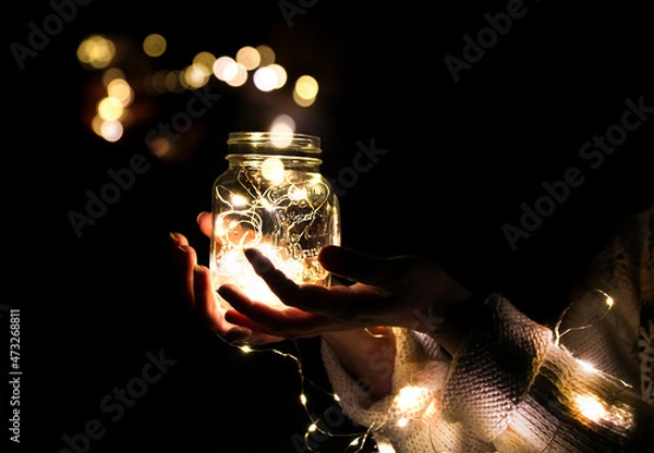 Obraz Hands holding a jar with a garland and a bokeh
