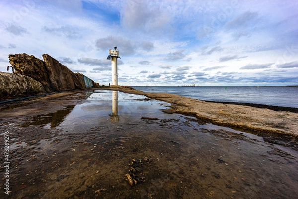 Obraz a big lighthouse stands at the end of the town mole