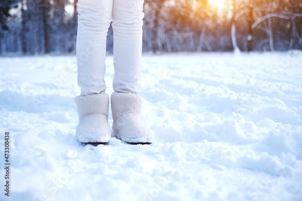 Obraz legs of a woman in fur boots on the snow in the forest. girl in warm shoes walks through the snowy forest. warm fur winter shoes