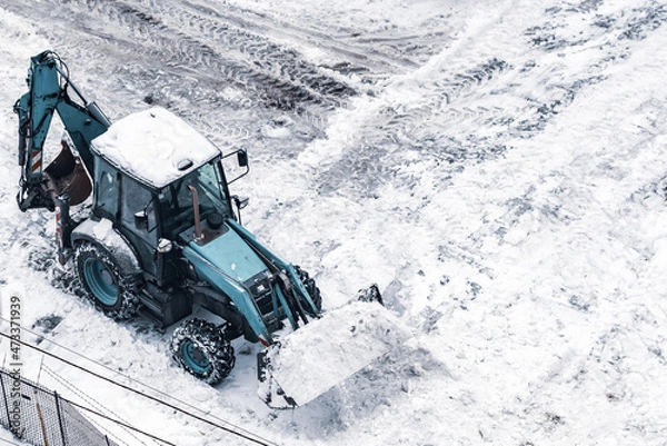 Fototapeta The tractor removes snow from the street after a snowfall