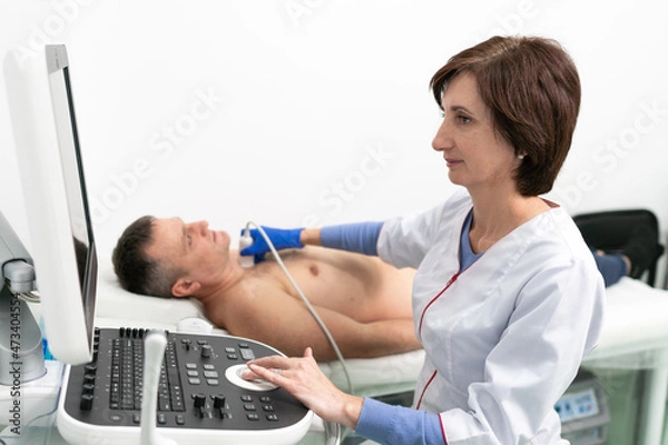 Fototapeta Doctor using ultrasound machine to scan heart of a male patient. Cardiologist makes a patient an echocardiographic test in a clinic. Patient under ultrasound examination in the hospital. 